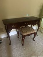 Vanity table and foot stool side view showing the dark wood finish and damask upholstery on the stool.
