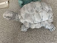 Side view of the grey resin turtle garden ornament showing textured shell, head, and legs.
