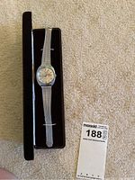Wittnauer mens watch inside its black velvet-lined case, laying on beige carpet