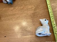Side view of the Beswick white ceramic cat figurine beside a measuring tape indicating about 4.5 inches in height.