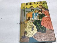 Front cover of the Little Women book showing four women in period clothing by a fireplace.