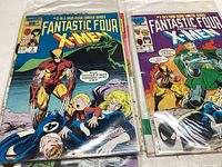 Photo showing the front covers of Fantastic Four vs X-Men comics, issues #2 and #1 with vivid cover art featuring Wolverine and other Marvel characters.