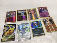 Top-down image showing all eight Pokémon cards laid out on a white surface.