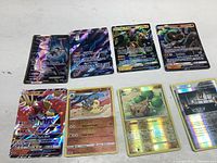 Eight Pokémon shiny and GX cards laid flat showing holographic foil and artwork including Ho-Oh GX, Tapu Koko GX, Mewtwo GX.