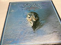 Front cover of The Eagles Greatest Hits vinyl record album with blue background and skull artwork.