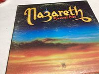 Front cover of Nazareth Greatest Hits vinyl record showing colorful sunset mountain horizon with yellow band logo.