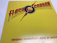 Front cover of the Flash Gordon soundtrack vinyl record with yellow background and large Flash Gordon logo. Text at the bottom states 'Original Soundtrack Music by Queen'.
