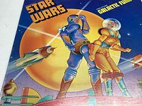 Close-up of the album artwork with two futuristic characters and a spaceship against a large yellow planet and blue background.
