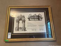 Full view of framed architectural print with gold distressed frame hanging on wall.