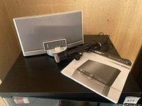 Bose SoundDock Portable stereo with Realistic Highball-7 microphone, remote control, and user manual on black table surface