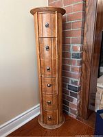 Full view of the round 6-drawer cabinet in a corner, showing round shape and wood panel design.