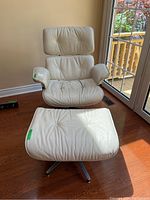 Front view of cream leather chair and ottoman set on hardwood floor by window