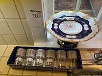 Dessert stand and boxed juice glasses displayed together on a tiled kitchen counter.