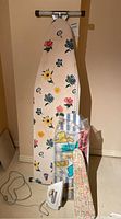 Full view of the large ironing board with floral cover and T-Fal iron at the base.