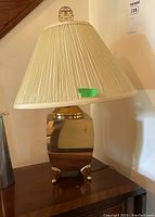 Full view of the table lamp showing the metal reflective base and pleated shade.