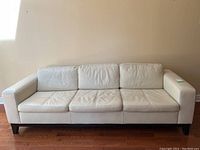 Front elevation showing full three-seat leather couch against wall