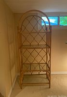 Front angled view of rattan shelving unit showcasing the lattice design and glass shelves