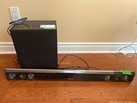 Sound bar and subwoofer speaker setup together showing front and side views, with visible dust on surfaces.
