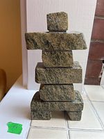 Front view of the carved Inukshuk sculpture showing stacked stone blocks and natural stone texture.