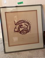 Framed artwork in metal frame with mat and glass showing full piece resting against a wall.