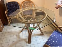 Square bamboo table with glass top in room with tile floor and bamboo chairs. Glass top is clear and removable, shows minor scratches.