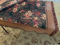 Photo of the cotton blanket showing the floral and autumn harvest design with patterned border and fringe.