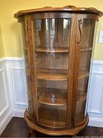 Front view of the oak china cabinet showing curved glass door and three interior shelves.