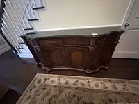 Photo of wooden dining room server showing front and side with ornate carved wooden details and multiple drawers and cabinet doors
