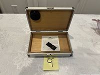 Open humidor showing wood interior, Ashton humidifier, and Ashton informational sheet inside.