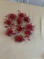 Group photo of 10 red decorative napkin rings showing full set with bead clusters.
