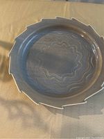 Top-down view of taupe-blue ceramic plate highlighting wave pattern and scalloped edges.
