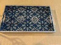 Full view showing rectangular blue, white and silver mosaic serving tray with handles.