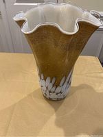 Full front view of the gold and white glass vase showing textured gold surface and ruffled white top edge.