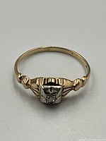 Top-down view of ring showing white gold-tone head with single diamond and decorative shoulders
