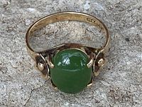 Front view of ring showing round green jade cabochon and floral details on shoulders
