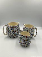 Front view of three floral-pattern Royal Winton Grimwades pitchers in varying sizes, positioned side by side.