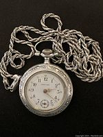 Pocket watch face-up with chain coiled, black background