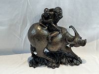 Front three-quarter view of the carved buffalo with two riders showing silver wire inlay patterns