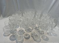 Overall display of 38 cut glass pieces on white drape