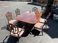 Overview of table and six chairs on pavement showing crossbanded top and shield-back chairs