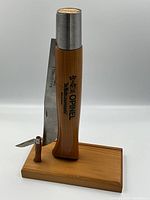 Frontal close-up photo showing the large Opinel cutting tool display stand with a miniature knife figure for size comparison.