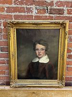 Full front view of framed oil painting of young boy against brick wall