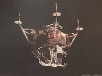 Close-up of color lunar module photograph showing module 'Spider' against black space and Earth's curvature