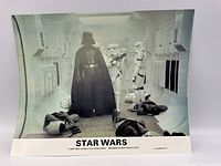 Color photo showing the front of the 8x10 Star Wars promotional material featuring Darth Vader and stormtroopers in a corridor with fallen figures on the floor.