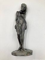 Front right angle of bronze sculpture showing figure’s frontal anatomy and draped cloth.