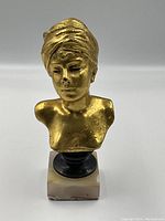 Front view of gilt bronze bust showing facial features, draped headwrap, plinth and onyx base.