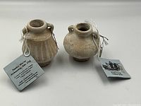 Front view of both jarlets showing their shapes and attached tags with historical information.