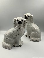 Front view of both white glazed dog figurines