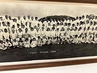 Close-up showing large group of children and adults seated and standing outdoors on grass in light clothing, marked 'Camp Hadar 1964'.