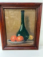 Front view of the framed still life oil painting showing the full artwork with a green bottle, two oranges on a plate, and a lemon in the background.